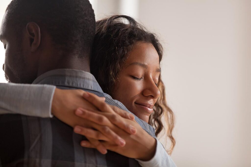 Close up young black american wife embracing partner.