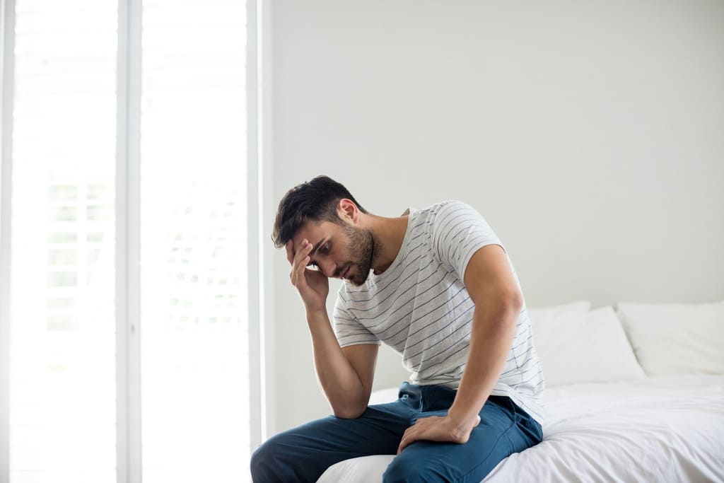 worried man sitting on a bed