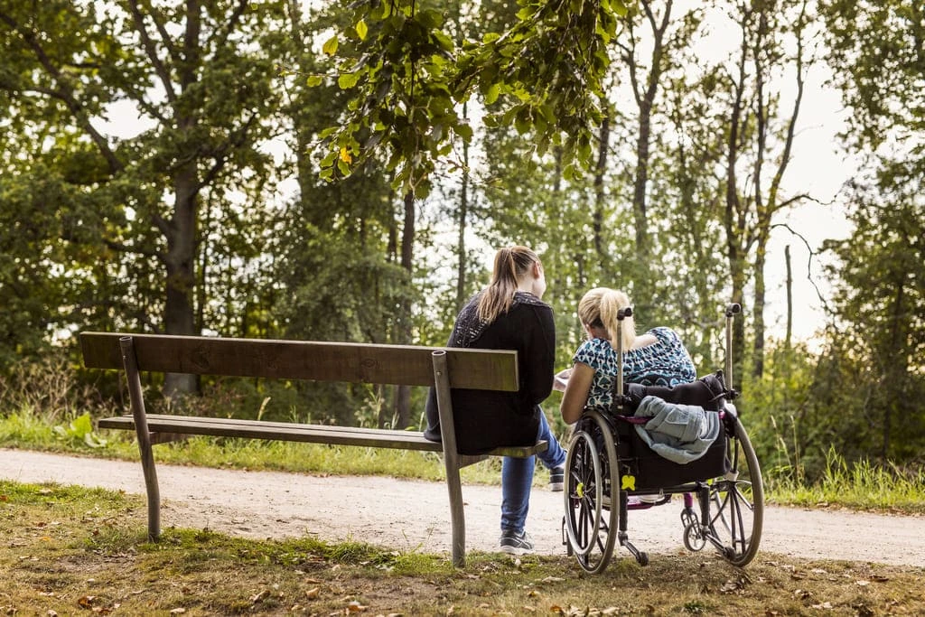 woman in wheelchair in the park with her support worker