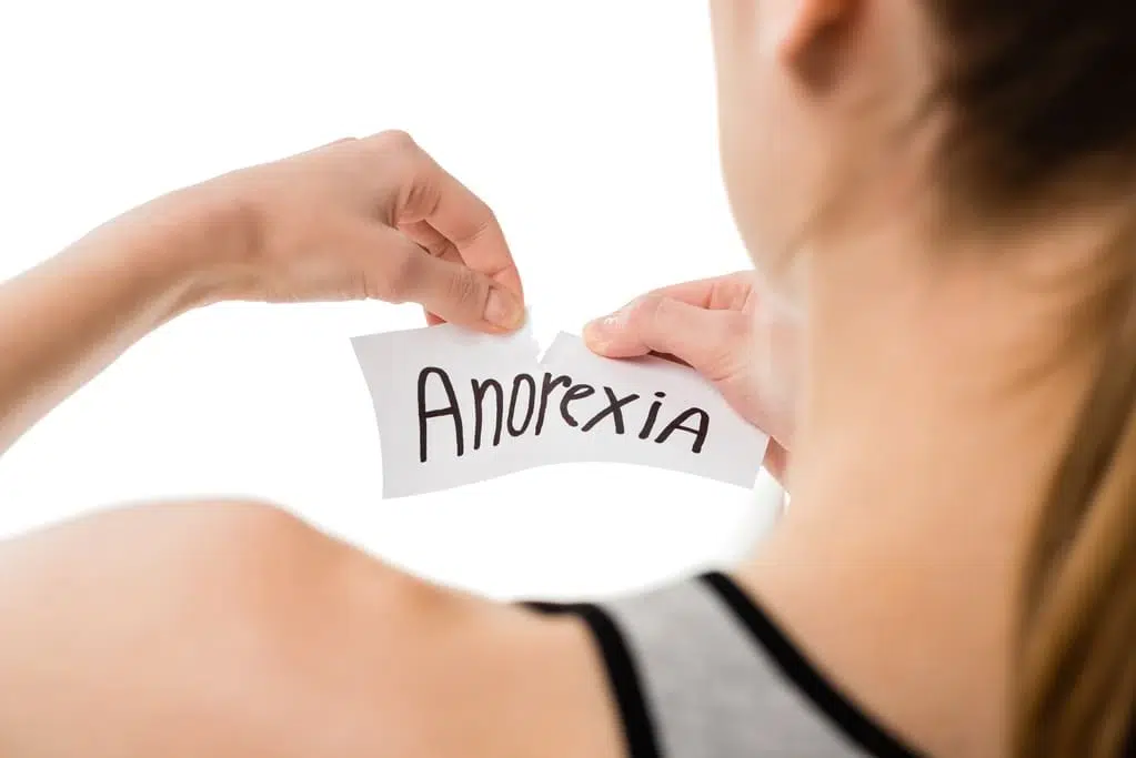 woman tearing up anorexia sign