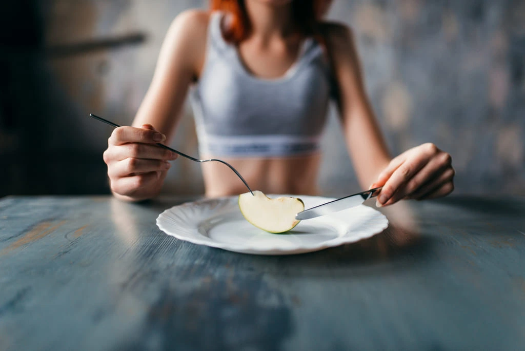 female sitting with a plate of an apple slice