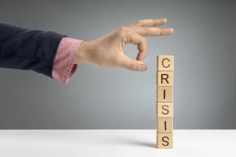 finger crashing tower of blocks that says crisis