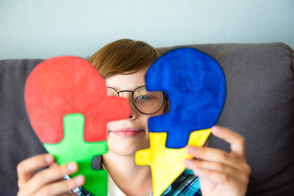 kid holding jigsaw puzzle in the shape of a heart