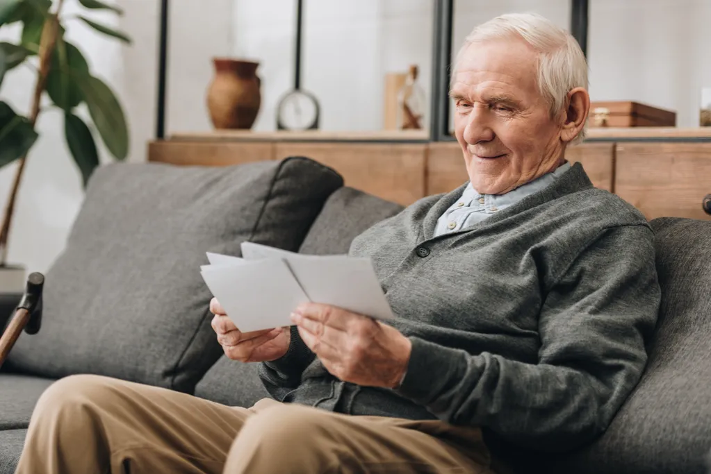 happy senior man with grey hair lookinf at photos 2022 12 16 16 15 32 utc